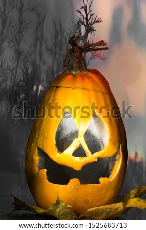 Halloween pumpkin on a background of blue mysterious forest. Ominous pumpkin with red luminous stripes. Vertical photograph. Orange-red jack head with a creepy smile. Halloween 2019
