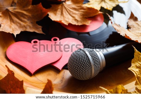 Song for lovers. Nostalgic songs, fallen autumn leaves and melancholy. Concept with vinyl records, microphone and hearts. Royalty-Free Stock Photo #1525715966