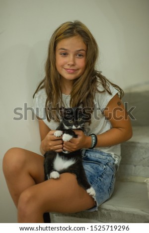 Pretty young caucasian girl with cute kitten. Teenager girl with a wary kitten. A child and a cat. A brunette girl with a pet at home. Life style. Beautiful cat in black and white with blue eyes