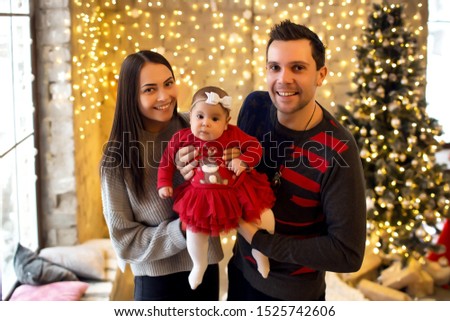 New Year or Christmas, portrait of a beautiful family, dad, mom and daughter near the New Year tree, Christmas evening, a tender and happy family in winter, father holds his daughter in his arms