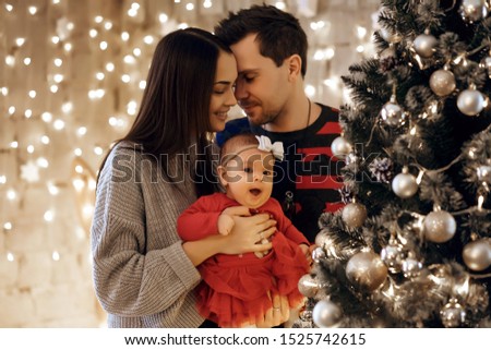 New Year or Christmas, portrait of a beautiful family, dad, mom and daughter near the New Year tree, Christmas evening, a tender and happy family in winter