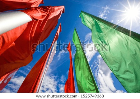 red and green flags set on flagpoles during the celebration of different holidays, flags on a blue sky background