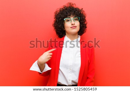 young pretty afro woman looking proud, confident and happy, smiling and pointing to self or making number one sign