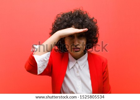 young pretty afro woman looking bewildered and astonished, with hand over forehead looking far away, watching or searching