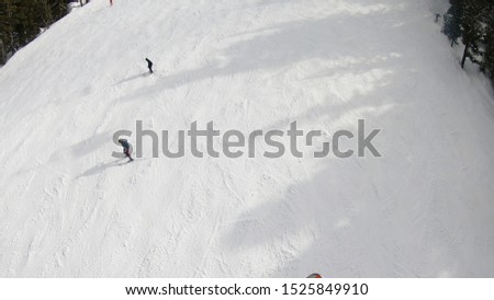 Chairlift elevation on the top of the peak. Aerial view of ski piste and skiers and snowboarder sliding down