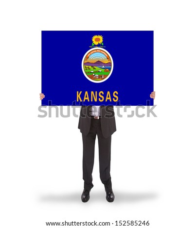 Smiling businessman holding a big card, flag of Kansas, isolated on white