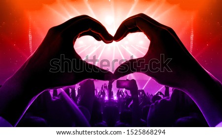 Happy people dance in nightclub party concert and listen to music from DJ on the stage in background. Cheerful crowd celebrate Christmas and New Year party 2020. Young people lifestyle and nightlife.