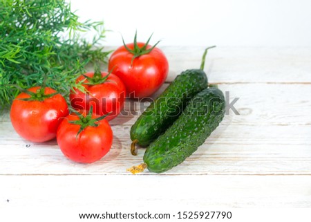 Harvest. Red tomatoes with a green stem. Fresh pimply cucumbers. Space for your text.