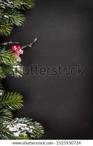 Christmas greeting card with fir tree branch over blackboard texture background. Xmas backdrop. Top view with copy space for your greetings