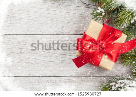 Christmas greeting card with gift box and fir tree branch over wooden texture background. Xmas backdrop. Top view with copy space for your greetings