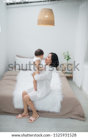 happy family. Mother and baby daughter plays, hugging, kissing at home on the bed