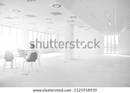 Black and white photo of businessman working on laptop in new empty office
