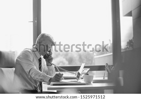Black and white photo of businessman talking on telephone in office