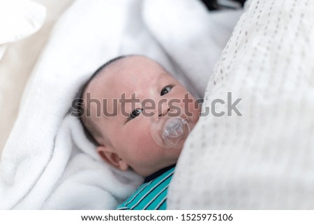Adorable baby boy lying down on bed with pacifier. Child is 4 months old