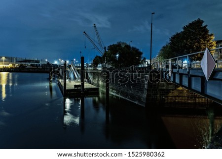 A concrete bridge over the water with a lot of lights under the blue sky at night time