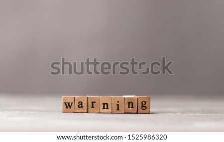 Warning word made of wooden stamps on working table