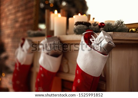Decorative fireplace with Christmas stocking and gifts in stylish room interior