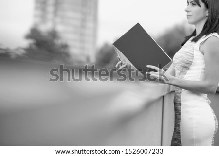 Black and white photo of businesswoman reading file on rooftop during break in office