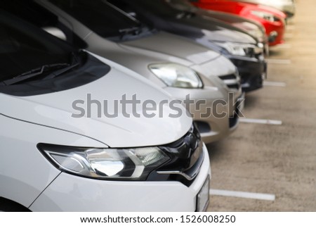 Closeup of front side of white car with  other cars parking in parking lot. The mean of simply transportation in modern world.