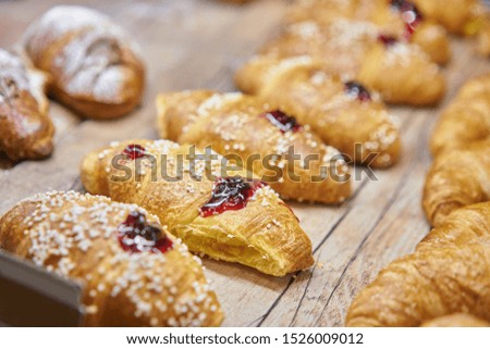 many of croissants with strawberry jam. Hot pastries lie on the showcase in the cafe. Buns and bagels in the store.