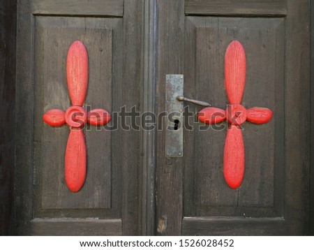 Photo of and old, rustic, decorative door with metal handle. Detail of wooden door with red ornate symbol.