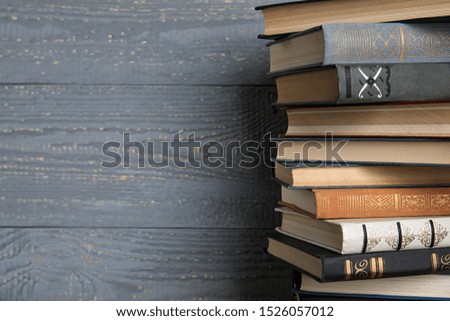 Stack of hardcover books on grey wooden background. Space for text