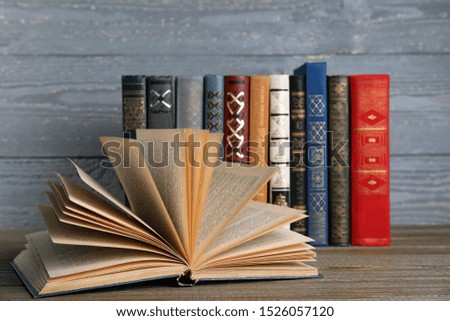 Stack of hardcover books on wooden table against grey background