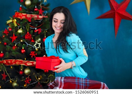 Smiling happy woman with gift box over living room on Christmas tree background. Holidays and people concept. Xmas time