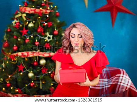 Smiling happy woman with gift box over living room on Christmas tree background. Holidays and people concept. Xmas time