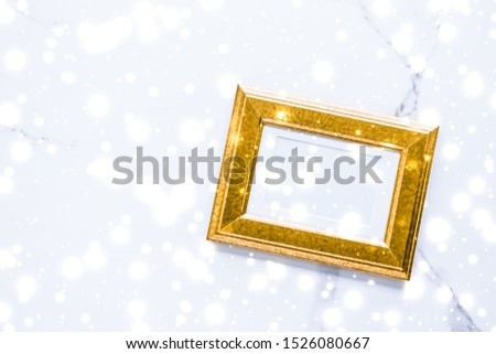 Art gallery, printable poster and online shop mockup concept - Golden photo frame and glowing glitter snow on marble flatlay background for Christmas and winter holidays