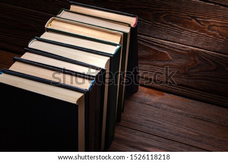 Old books . I used a number of old closed books with hardcover in dust on dark wooden background. Books textbooks for reading and education.