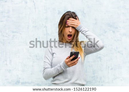 young pretty woman with a smart phone against grunge wall