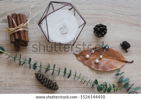 Botanic bridal chic. Bouquet with silk ribbons, earrings, wedding rings and engagement ring on wooden background.