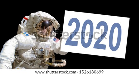 Astronaut in space holding a 2020 white  board - New year greeting card - elements of this image are provided by NASA Royalty-Free Stock Photo #1526180699