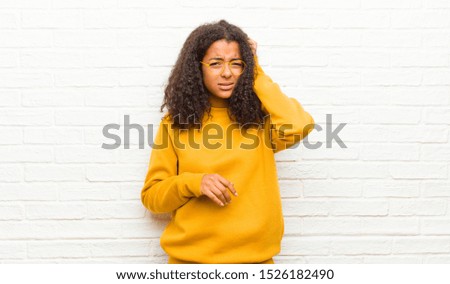 young black woman feeling stressed, frustrated and tired, rubbing painful neck, with a worried, troubled look against brick wall