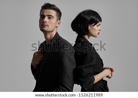 woman and man stand with their backs to each other in dark clothes short haircut wig love family