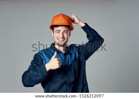 engineer in orange helmet shows thumb and blue suit