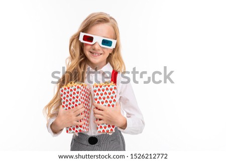 A little girl with long blonde hair in her glasses 3-D with popcorn.
