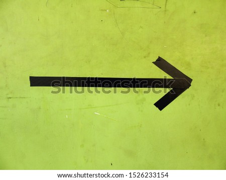 photo of a black arrow on the wall, symbol of direction.