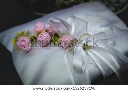 Upclose wedding rings. Silver wedding ring on silk cloth. Pink flowers decoration.