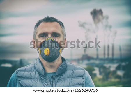 Man wearing a real anti-pollution, anti-smog and viruses face mask; dense smog in air. Royalty-Free Stock Photo #1526240756