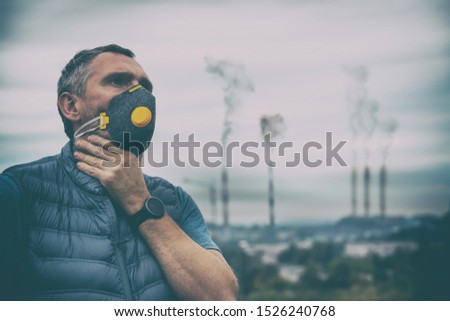 Man wearing a real anti-pollution, anti-smog and viruses face mask; dense smog in air. Royalty-Free Stock Photo #1526240768