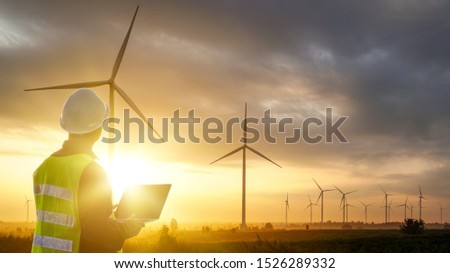 Silhouette of Technician Engineer  at wind turbine electricity industrial in sunset Royalty-Free Stock Photo #1526289332