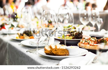 Sparkling glassware stands on long table prepared for wedding dinner