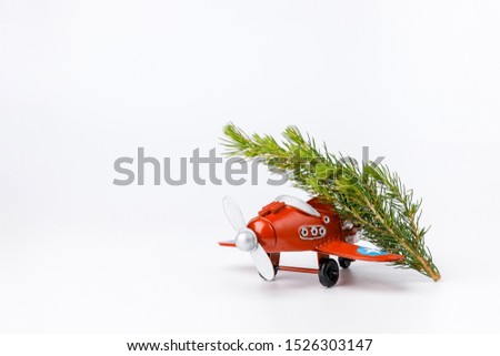 Miniature toy red retro airplane with little fir tree  on white background. Metal model.