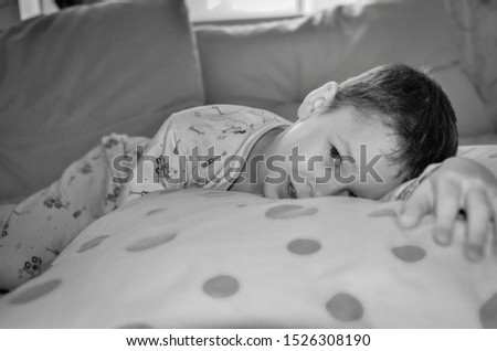 Pajama party on the bed, a little boy indulges in pillows. Battle pillows in pajamas. Very emotional black and white photo.