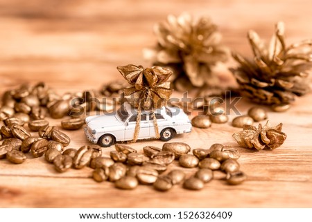 Little toy car with cookie and candy,Golden paint on coffee beans, cozy christmas on wooden background