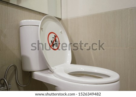 Close up photo of white toilet bowl with do not trash sign.