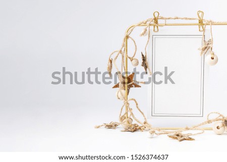 Little fir tree in ceramic vase and golden frame on white background. Christmas card - toys, garlands and wooden thinks.