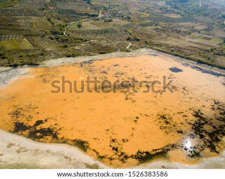 water reservoir covered in orange algae making it look surreal lake from above. picture taken with drone in tepelene Albania